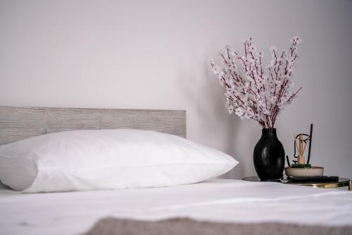 a bed with a white pillow and a vase with flowers at Most - Bitka za ranjenike na Neretvi in Jablanica