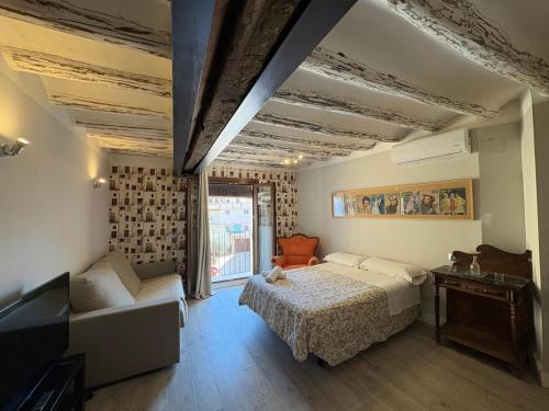 a bedroom with a bed and a couch and a tv at Apartamentos Vino Tinto y Restaurante Tomate Rosa in Adahuesca