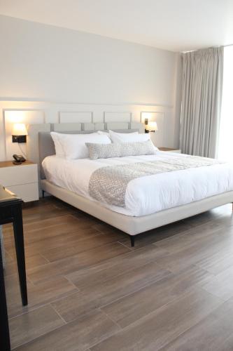 a bedroom with a large white bed and a wooden floor at OTMÁNN Hotel Boutique in Guadalajara