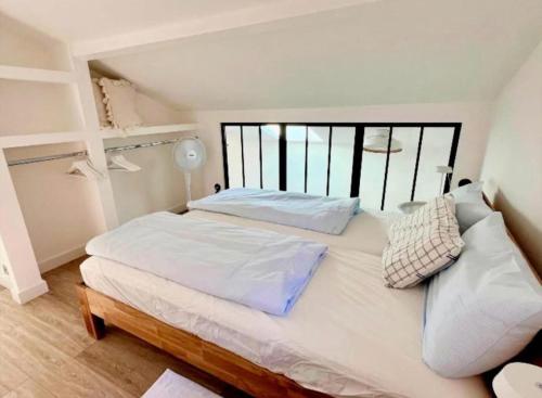a bedroom with a large white bed and a window at Contemporary-style pavilion in Narbonne