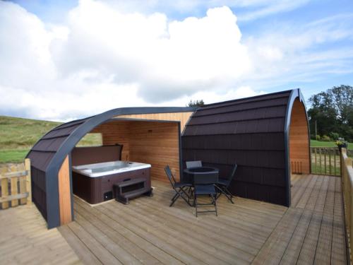 a small black shed with a grill and chairs on a deck at 1 Bed in Teviothead 75346 in Hawick