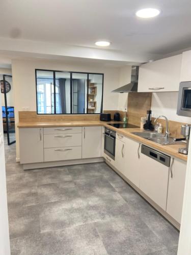 une cuisine avec des armoires blanches et un comptoir dans l'établissement Appartement coeur centre ville et parking gratuit, à Bayeux