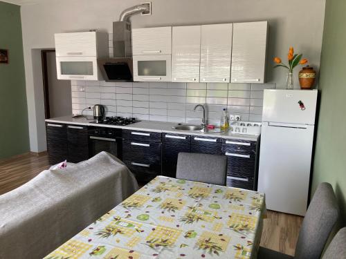 a kitchen with a table and a white refrigerator at Apartament Villa Olivia in Szczebrzeszyn