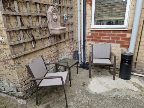 three chairs and a table next to a brick wall at West Beck House - Newcastle 1 in North Shields