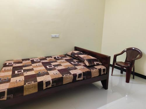 a bed and a chair in a room at Murugavel Residency in Vishāram