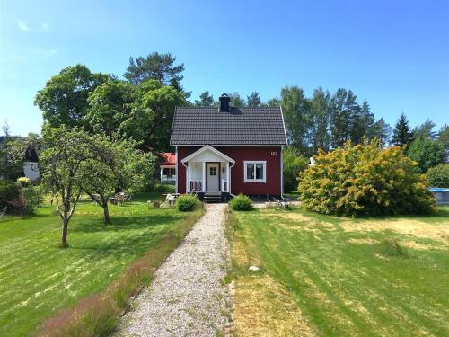 a red and white house in a grassy yard at RiverNest Bergsäng- Natur- Ruhe- Abenteuer in Bergsäng