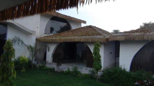 a white house with a thatched roof at Risacca Crown in Jaipur