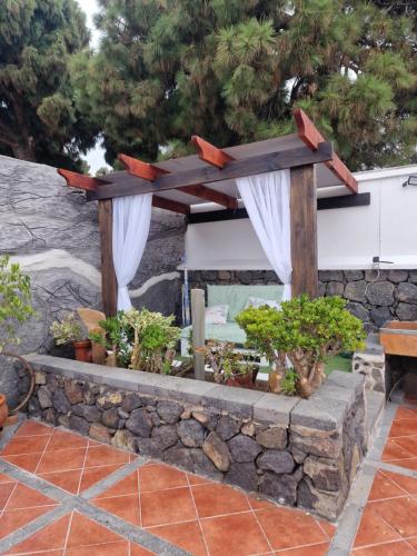 a stone retaining wall with a pergola with plants at La Chosita in Icod de los Vinos
