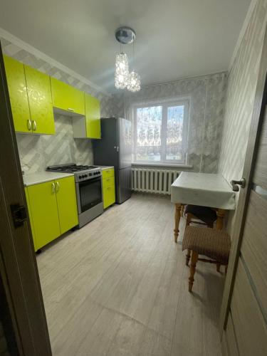 a kitchen with yellow cabinets and a sink and a table at Квартира in Borovoye