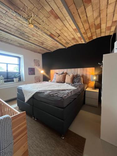 a bedroom with a large bed with a wooden ceiling at Wohnen im ehemaligen Kuhstall Stiehler Farm in Treia