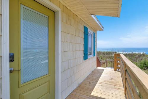a house with a door and a balcony with the ocean at Reelaxing in Oak Island