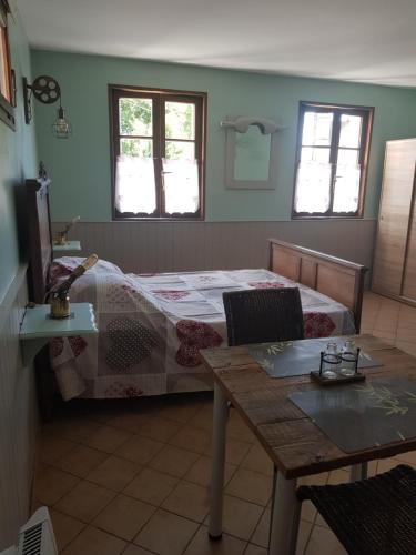 ein Schlafzimmer mit einem Bett und einem Tisch und zwei Fenstern in der Unterkunft Entre Terre et Mer Le Haut Bois in Guisy
