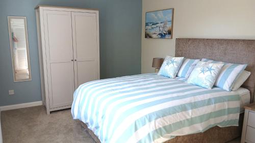 a bedroom with a bed with a striped comforter at Stylish Seaside Cottage - 3 minute walk to beach with parking in Skegness