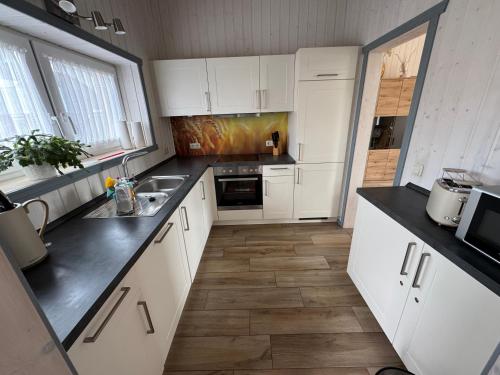 a kitchen with white cabinets and black counter tops at Seeschwalbe 78 Kompassweg in Rechlin
