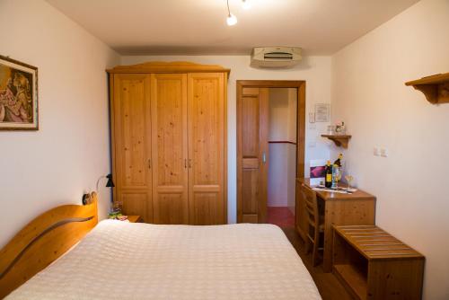 sypialnia z łóżkiem i drewnianą szafką w obiekcie Bajta Fattoria Carsica w mieście Baita