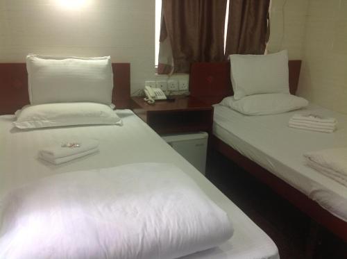 two beds in a room with white sheets and pillows at New Yan Yan Guest House reception 9th floor Flat E4 E6 in Hong Kong