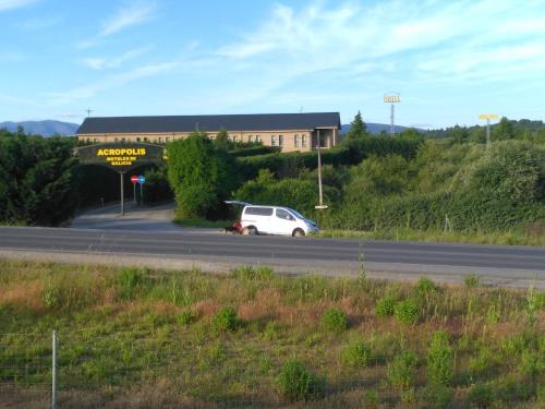a white car driving down a road in front of a building at Motel Acropolis in Camponaraya