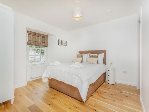 a white bedroom with a large bed and wooden floors at Sandakan in Ardersier