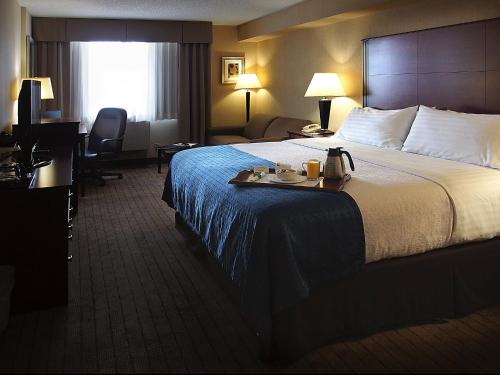 a hotel room with a large bed with a tray on it at Holiday Inn & Suites Winnipeg Downtown by IHG in Winnipeg