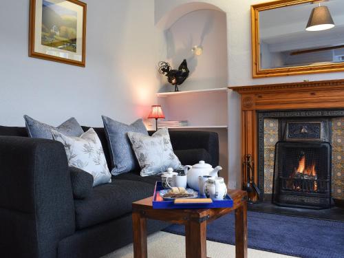 ein Wohnzimmer mit Couch und Kamin in der Unterkunft Ardchoille Cottage in Fortingall