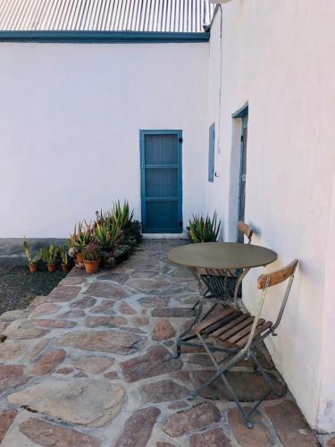a table and chairs sitting on a patio with a blue door at Sister Alice in Nieu-Bethesda