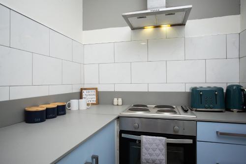 a kitchen with a stove and a white tiled wall at Chic 3BR Apartment - City Views, Fast WiFi & Close to Train Station! in Newcastle upon Tyne
