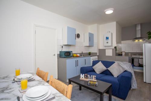 a living room with a blue couch and a table at Chic 3BR Apartment - City Views, Fast WiFi & Close to Train Station! in Newcastle upon Tyne