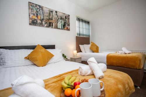 a hotel room with two beds with fruit on a table at Chic 3BR Apartment - City Views, Fast WiFi & Close to Train Station! in Newcastle upon Tyne