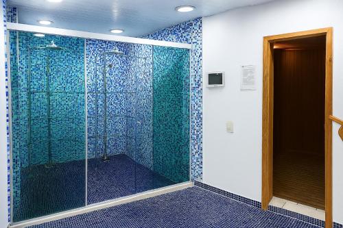 a bathroom with a glass shower with blue tiles at BOOK A FLAT Gran plaza Paulista in Sao Paulo
