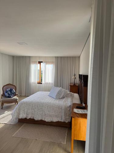 a bedroom with a large bed and a chair at Hotel Boutique Canto da Seriema in Tiradentes