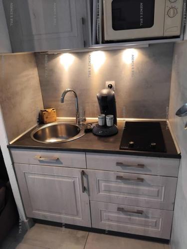 une petite cuisine avec un évier et un micro-ondes dans l'établissement Résidence Héliopolis Bâtiment Fgh - STUDIO 2 pers. HELIOPOLIS FGH MAE-5271, au Cap d'Agde