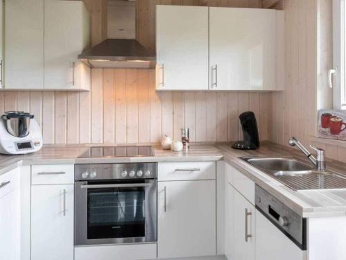 Huus Naturstrand am Diek في Wesselburen: مطبخ بدولاب بيضاء وموقد ومغسلة