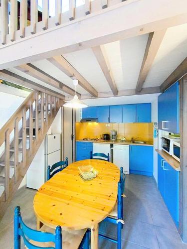 une table en bois dans une cuisine avec des armoires bleues dans l'établissement Résidence Coulemelles - Maison mitoyenne 6 pers, cote Atlantique, Lacanau océan MAE-1091, à Lacanau