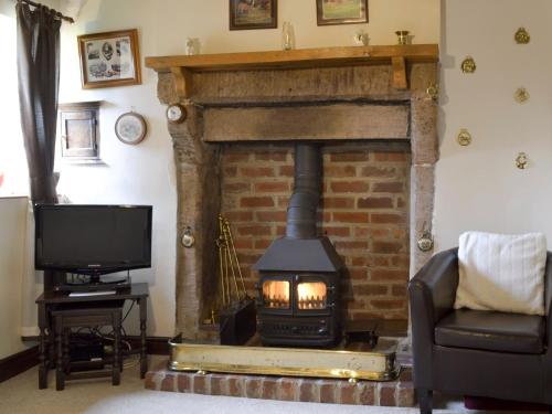 a living room with a fireplace and a tv at Ivy Cottage in Elton