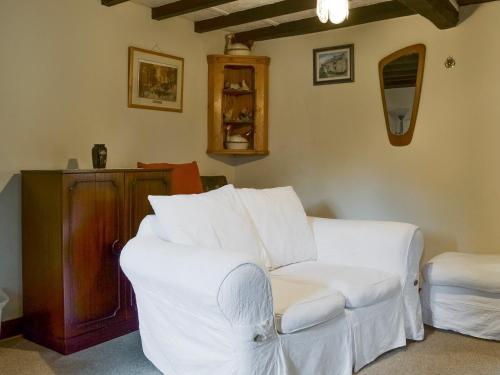 a living room with a white couch and a stool at Ivy Cottage in Elton