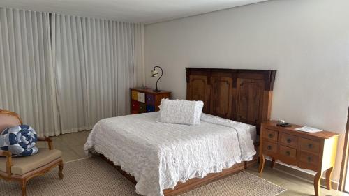 a bedroom with a bed and a chair and a dresser at Hotel Boutique Canto da Seriema in Tiradentes