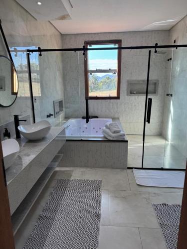 a bathroom with a tub and a sink and a shower at Hotel Boutique Canto da Seriema in Tiradentes