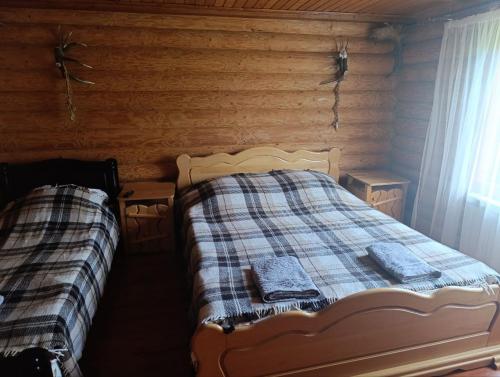 a bedroom with two beds in a log cabin at Лісовик in Synevyrsʼka Polyana