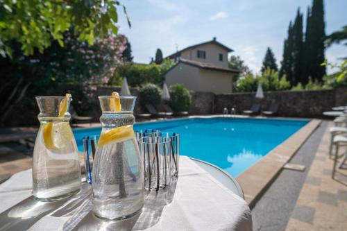 two glass vases sitting on a table next to a swimming pool at Borgoluna Luxury Holiday House in San Felice del Benaco