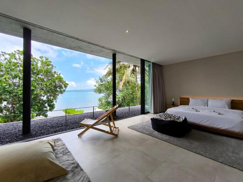 a bedroom with a bed and a view of the ocean at Luxury Beachfront AMANA Villa 4 Br at Ta-Ke Residence A in Phuket