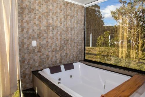 a bath tub in a bathroom with a large window at Cabanas Antonelli in Caxias do Sul