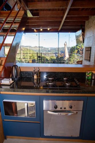 a kitchen with a stove and a large window at Cabanas Antonelli in Caxias do Sul