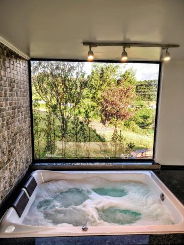 a bath tub with a large window in a room at Cabanas Antonelli in Caxias do Sul
