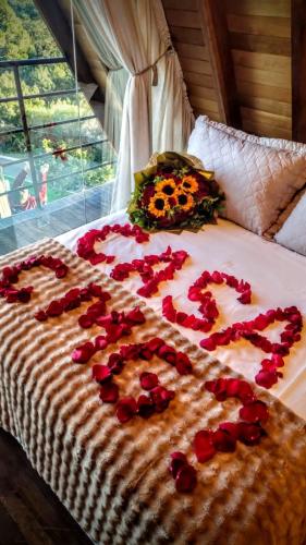 a bed with rose petals spelling out the word love at Cabanas Antonelli in Caxias do Sul