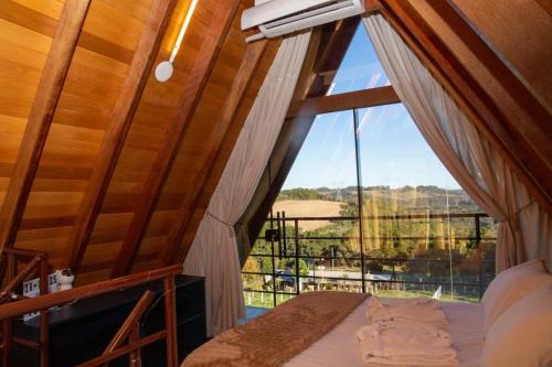 a room with a bed and a large window at Cabanas Antonelli in Caxias do Sul