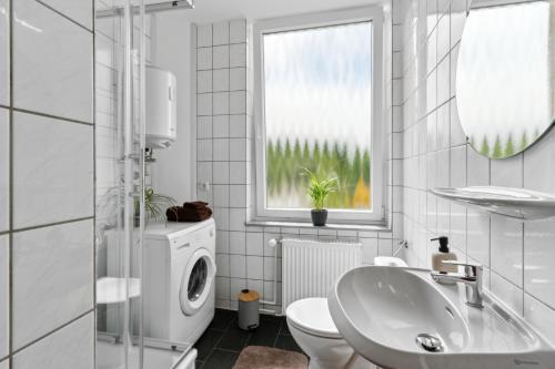a white bathroom with a sink and a washing machine at Business Apartment Alte Post in Unterlüß