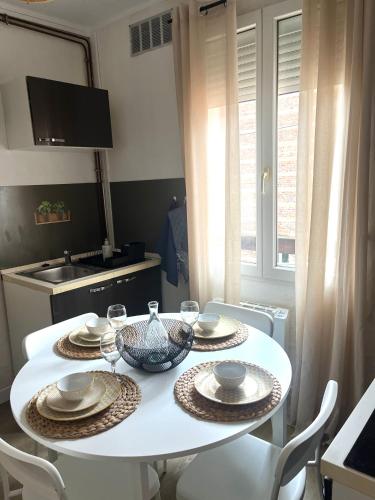 appartement coconing في لو هافر: طاولة بيضاء عليها أطباق وأوعية في المطبخ