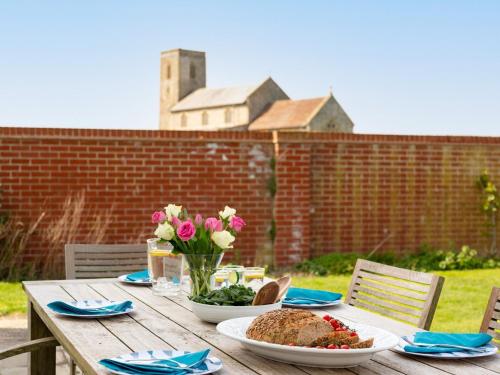 a wooden table with plates of food and flowers on it at 4 Bed in West Runton 81469 in West Runton