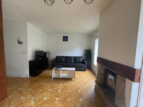 a living room with a couch and a fireplace at Maison en campagne avec chambre mezzanine in Priziac