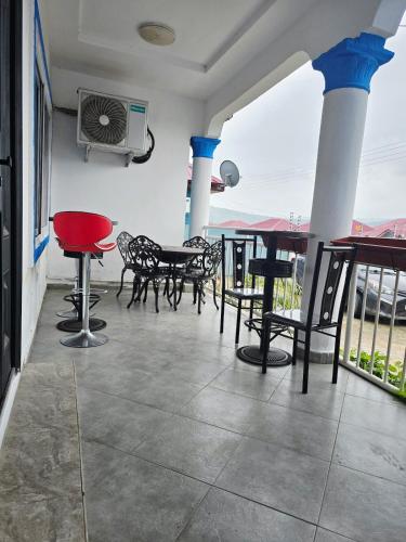 eine Terrasse mit Tischen und Stühlen auf einem Balkon in der Unterkunft Niji Luxury studio apartments in Amasaman